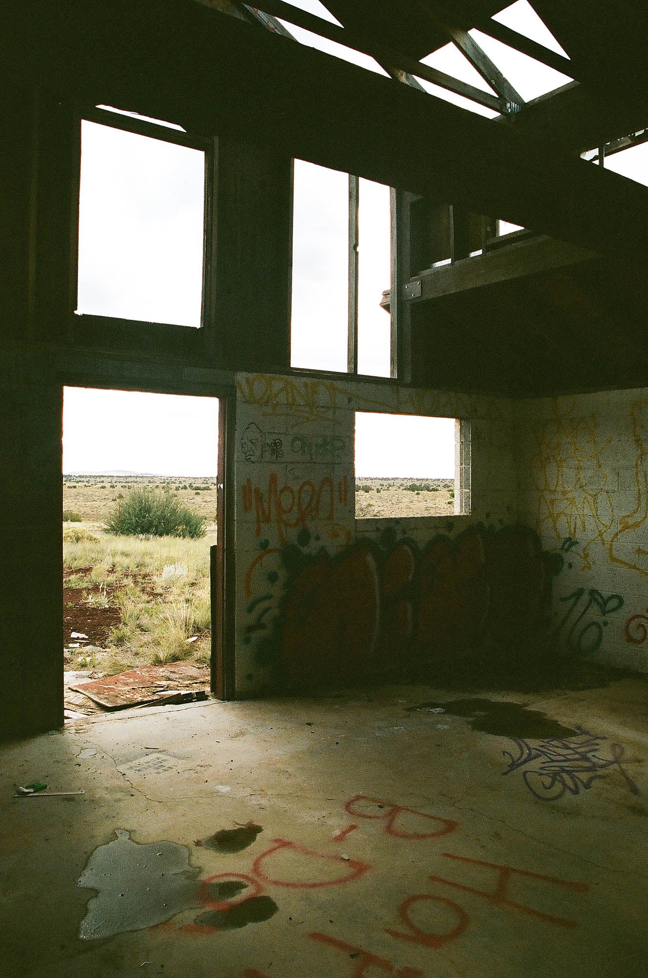 The interior of an abandoned barn structure with graffiti on the floor