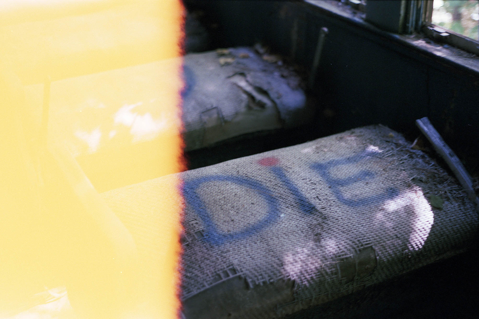 A worn wicker train seat with DIE spray painted on it