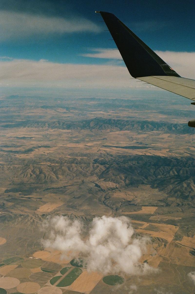 Utah landscape from the air, with a single cloud and the tip of a plane wing