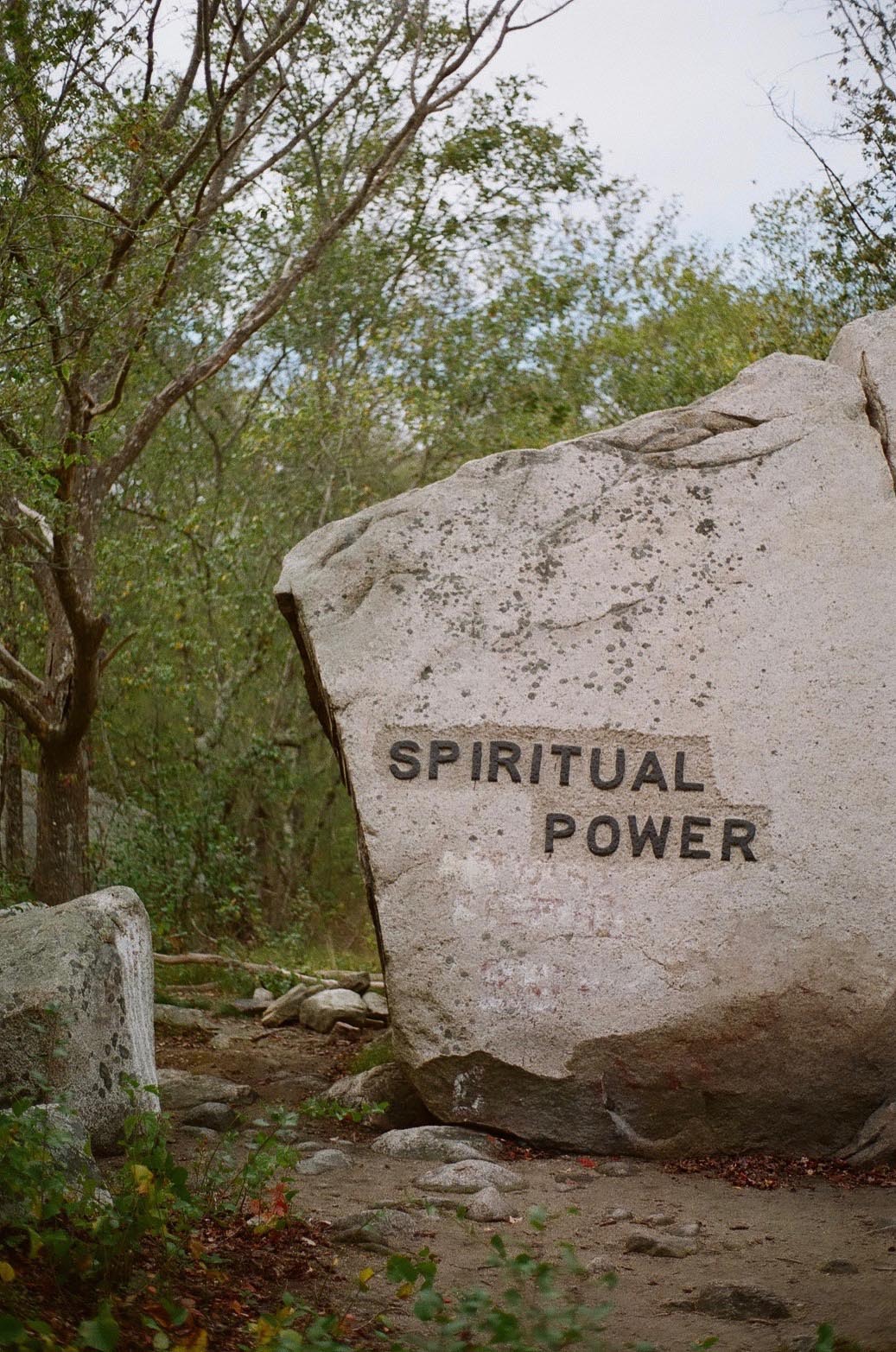 A boulder in the woods carved with the phrase: Spirital Power