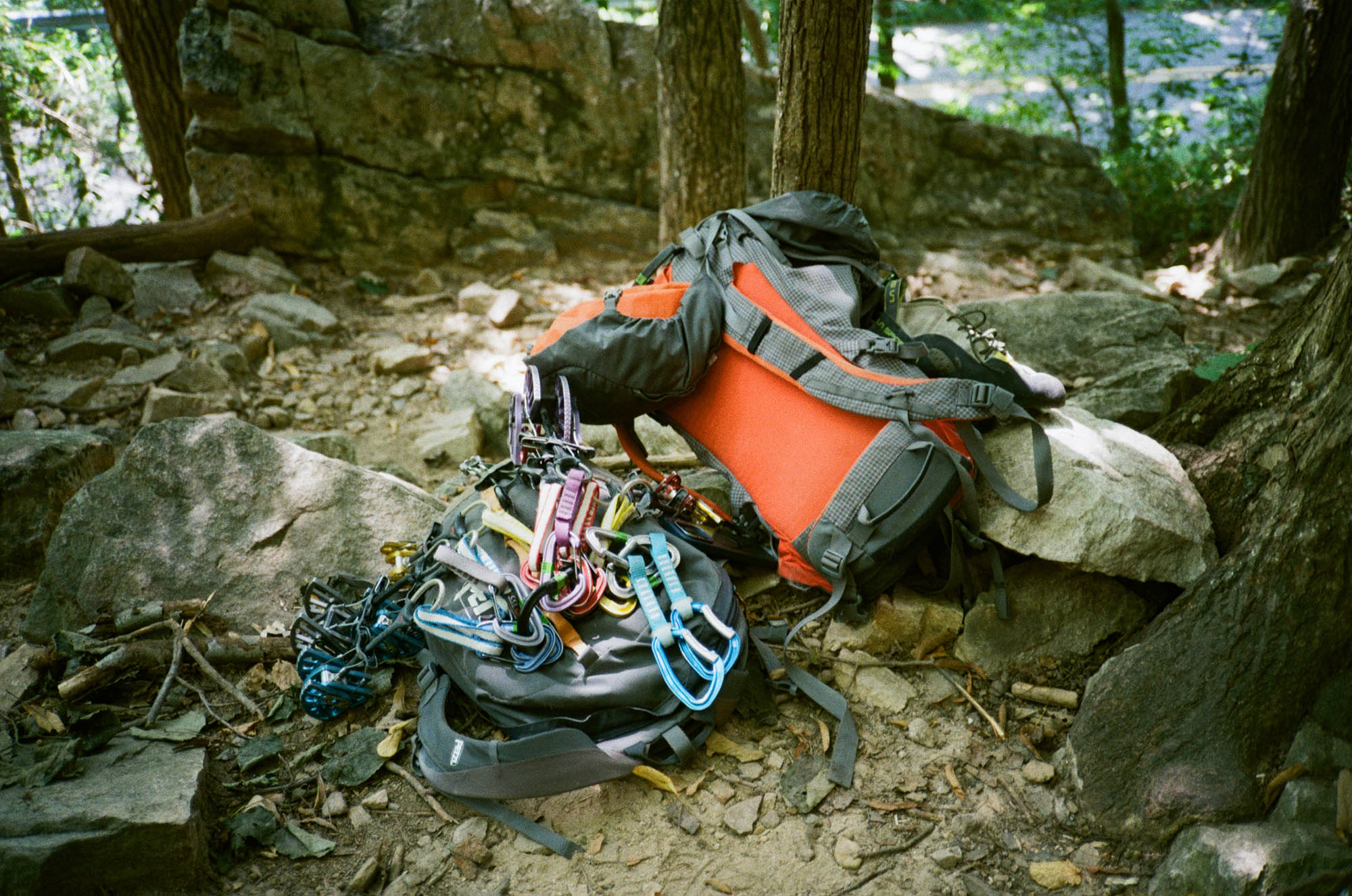 A colorful backpack with a pile of quickdraws and carabiners