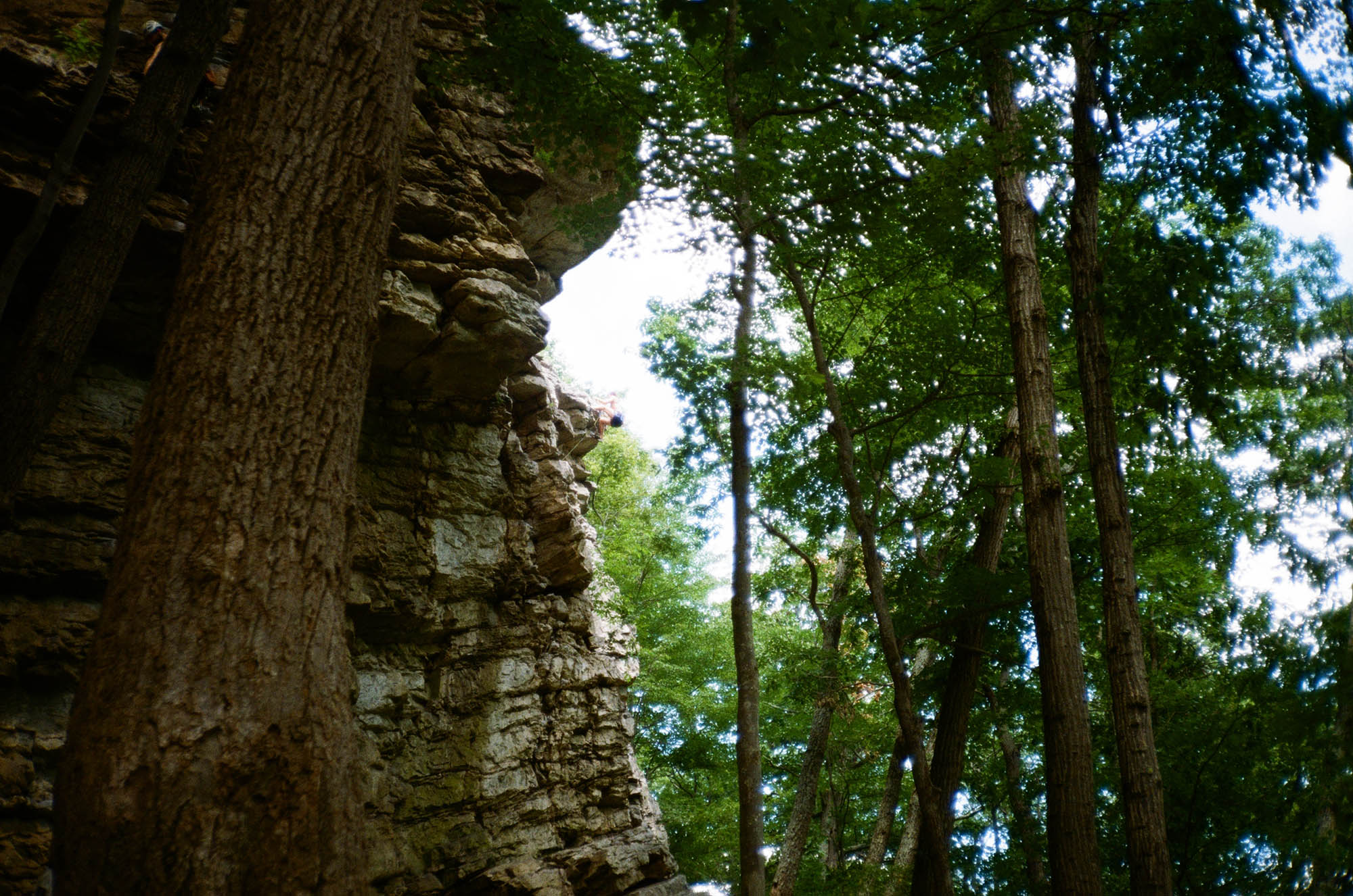A person climbing on the edge of a rock wall in the distance