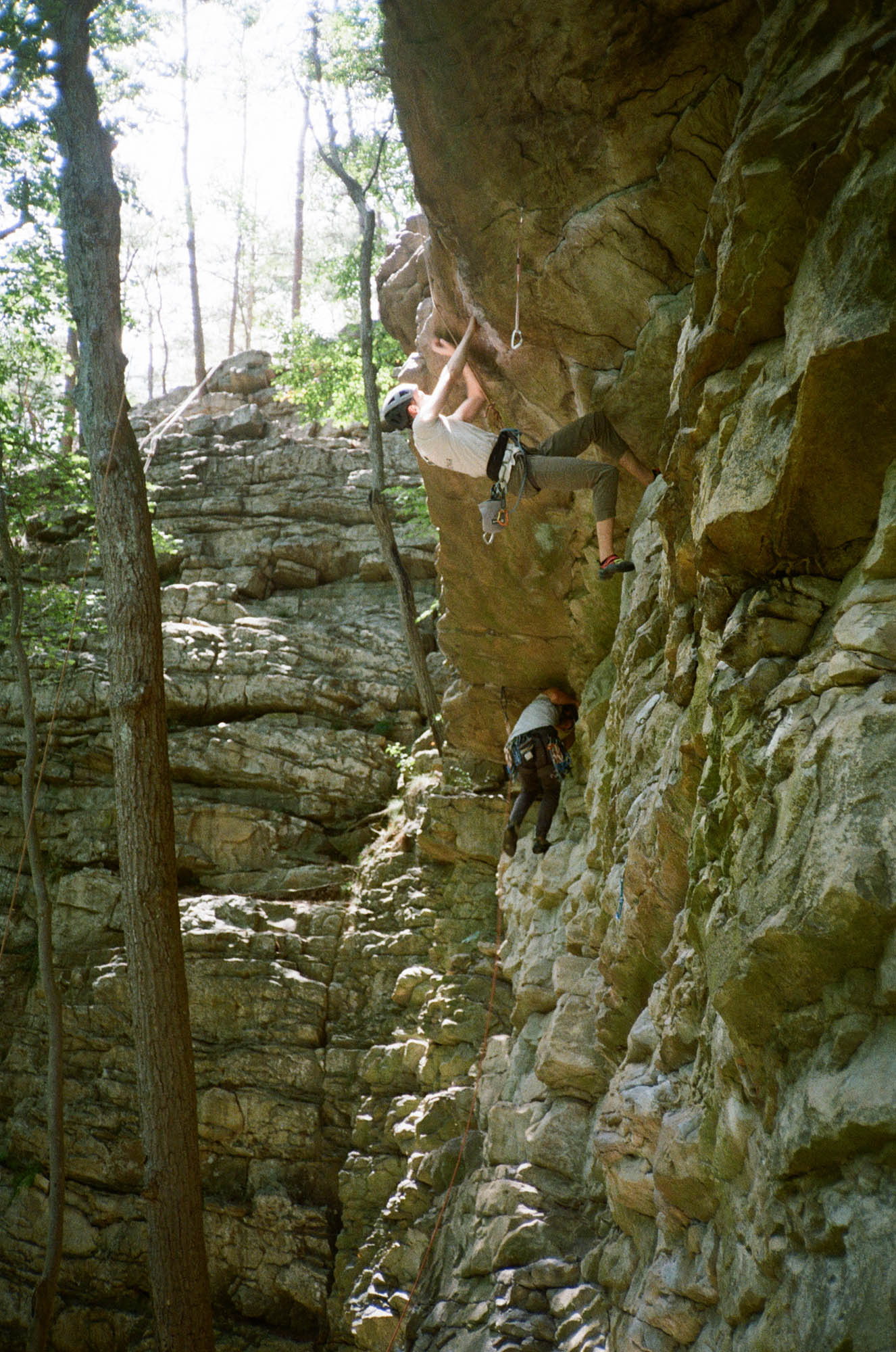 Two people simultaneously climbing a rock wall at a steep overhang