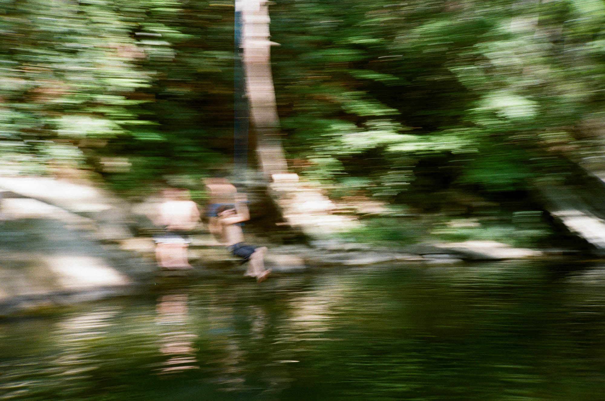 A blurred picture of a person on a rope swing above a river