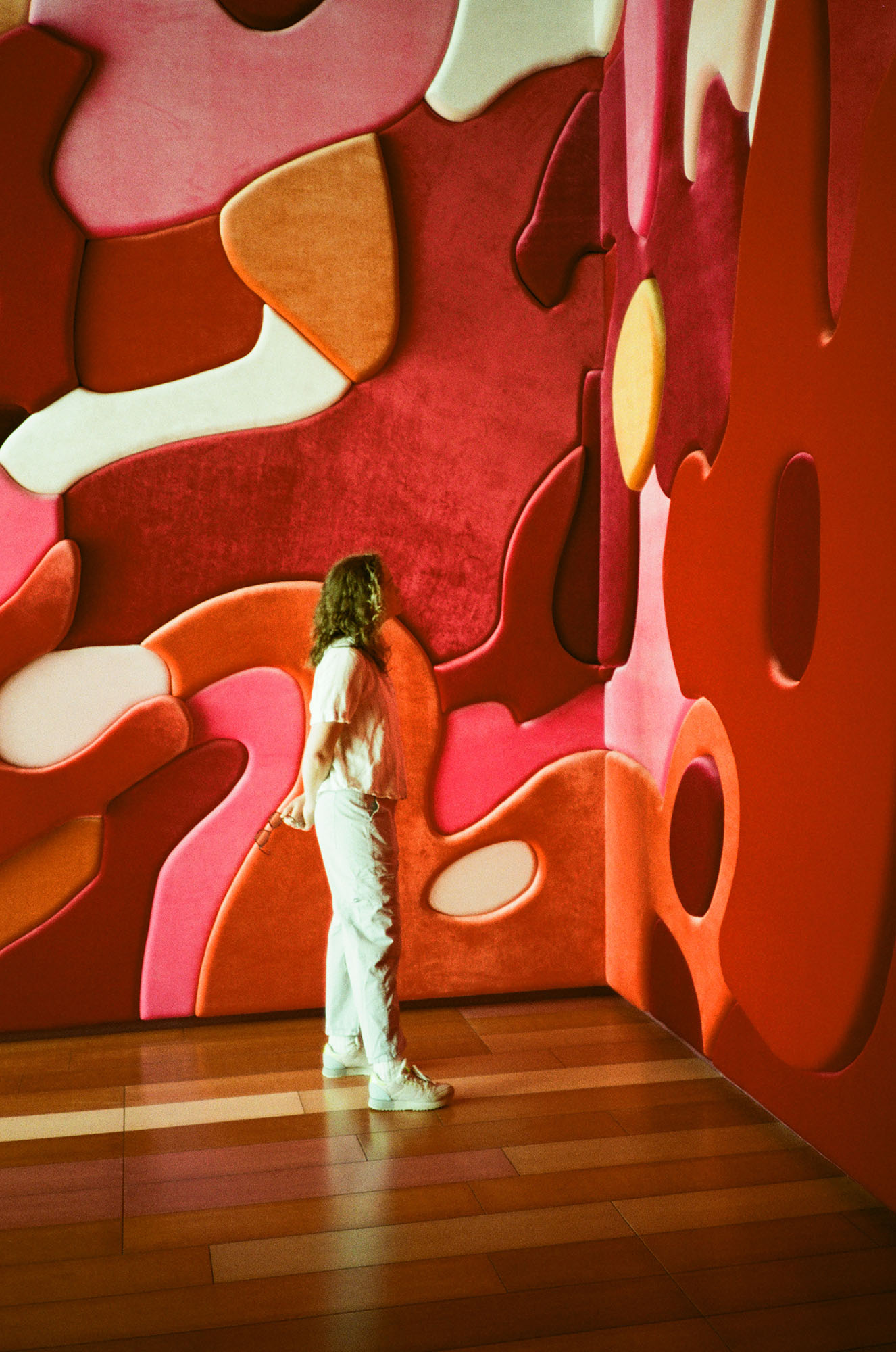 A person looking at a wall covered in curvy velvet shapes