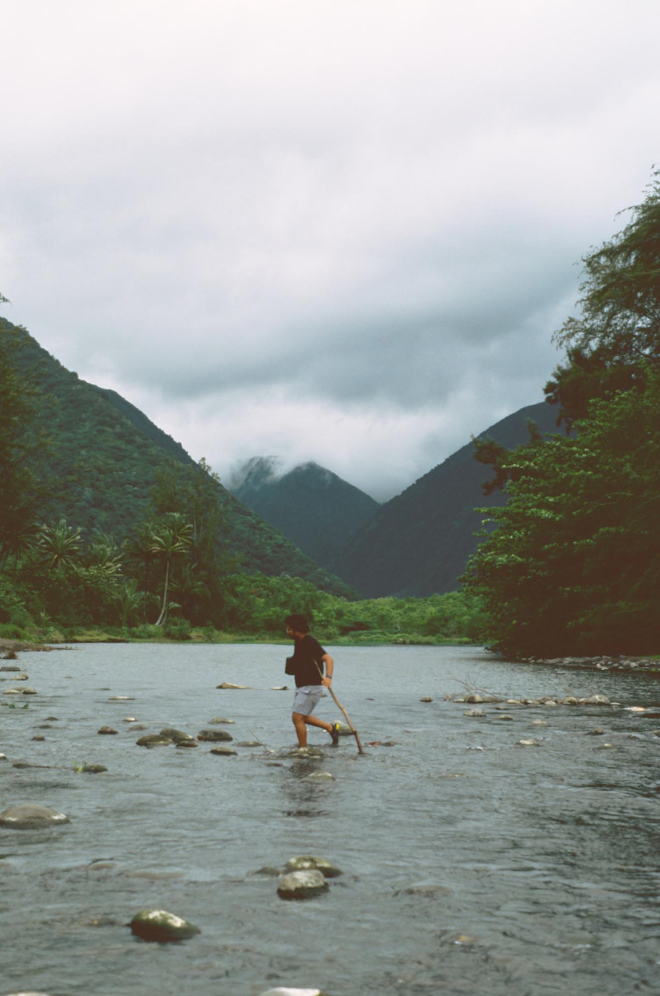 A person wading across a river with the valley in the distance