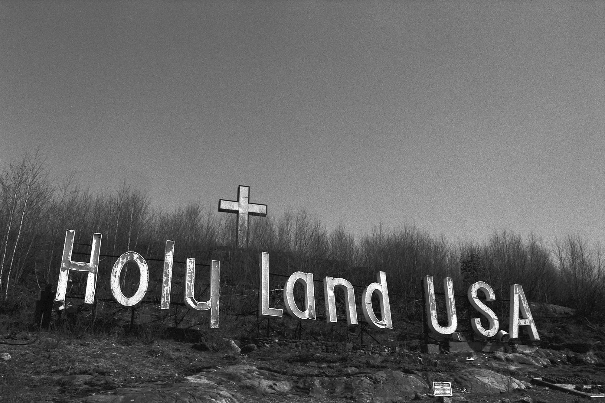 A Hollywood Sign-style sign that says Holy Land USA with a cross in the distance