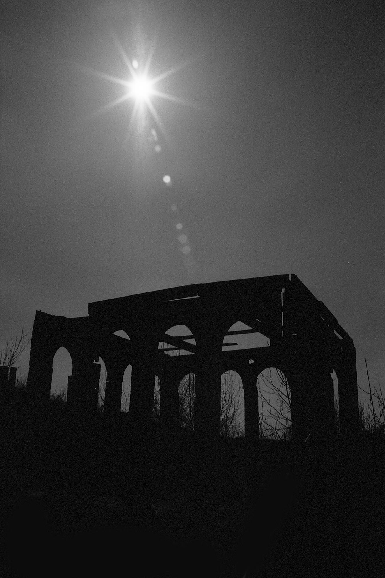 The silhouette of a decaying miniature building with the sun in the sky