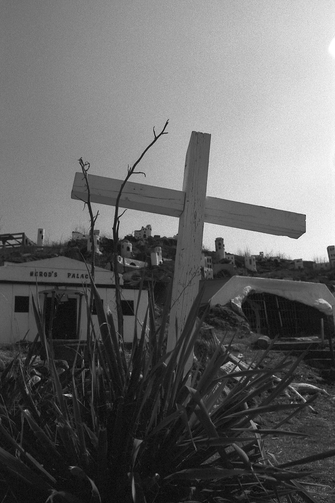 A leaning cross in front of a decaying miniature town