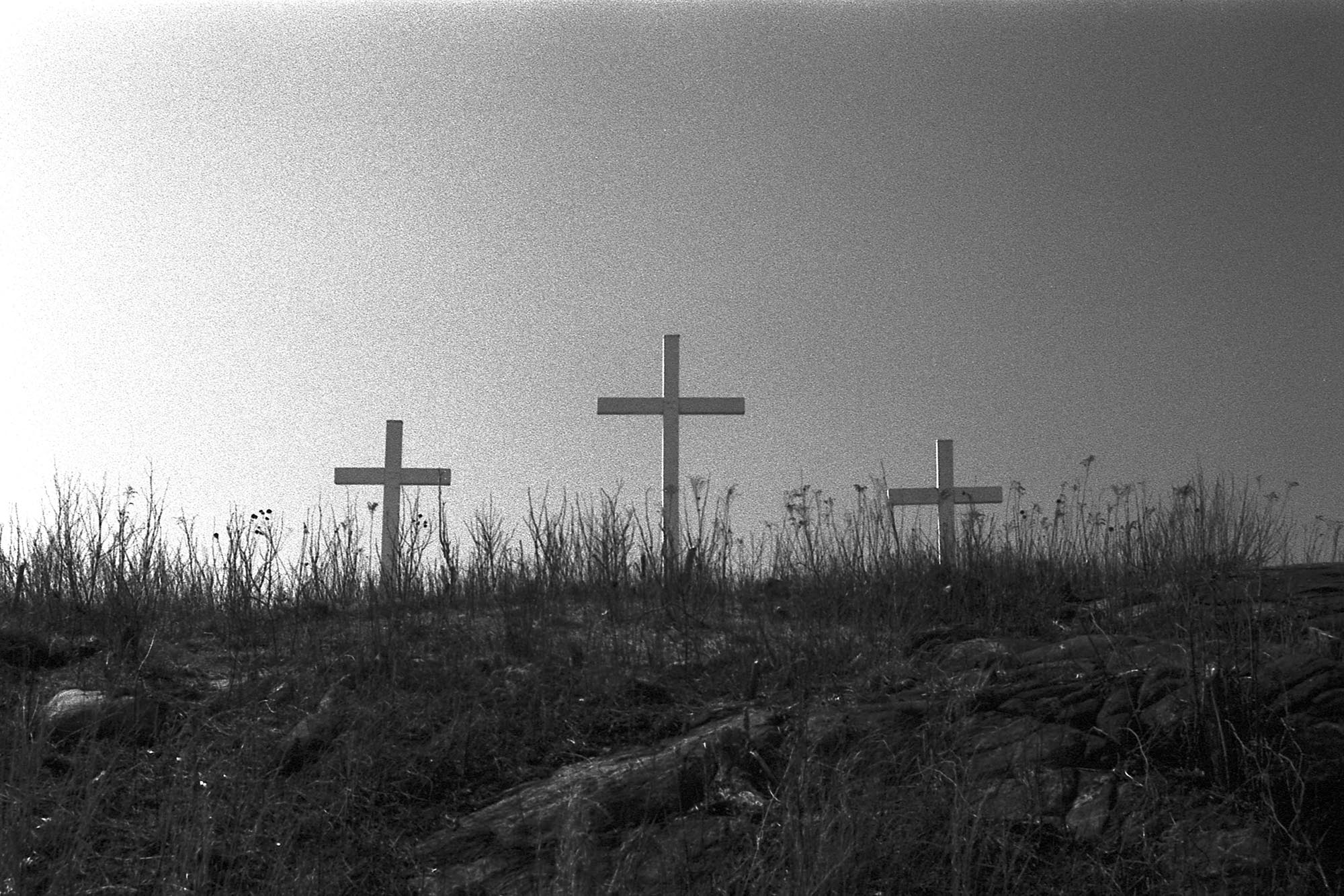 Three wooden crosses on a hillside