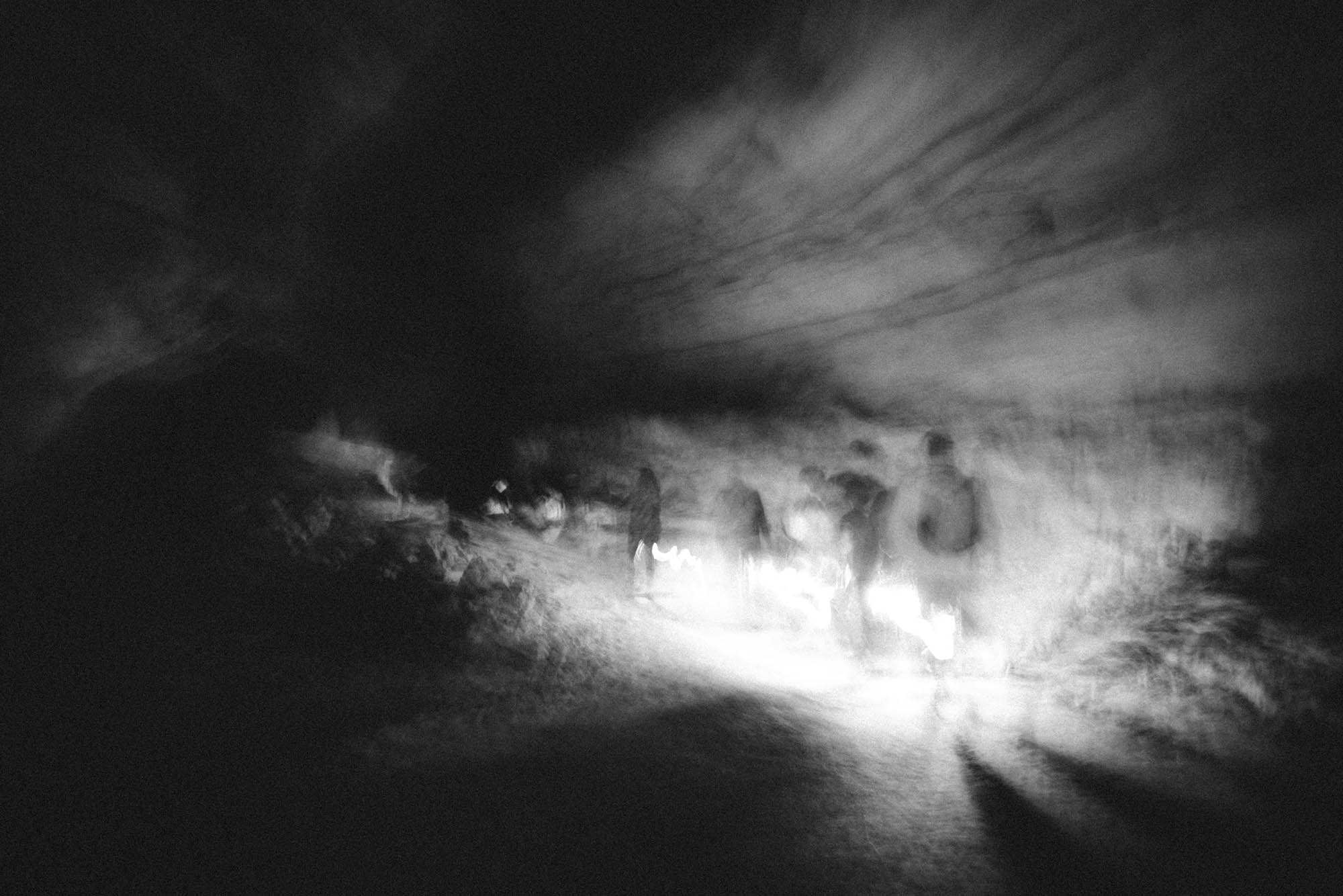 Blurry silhouettes walking in a lantern-lit cave