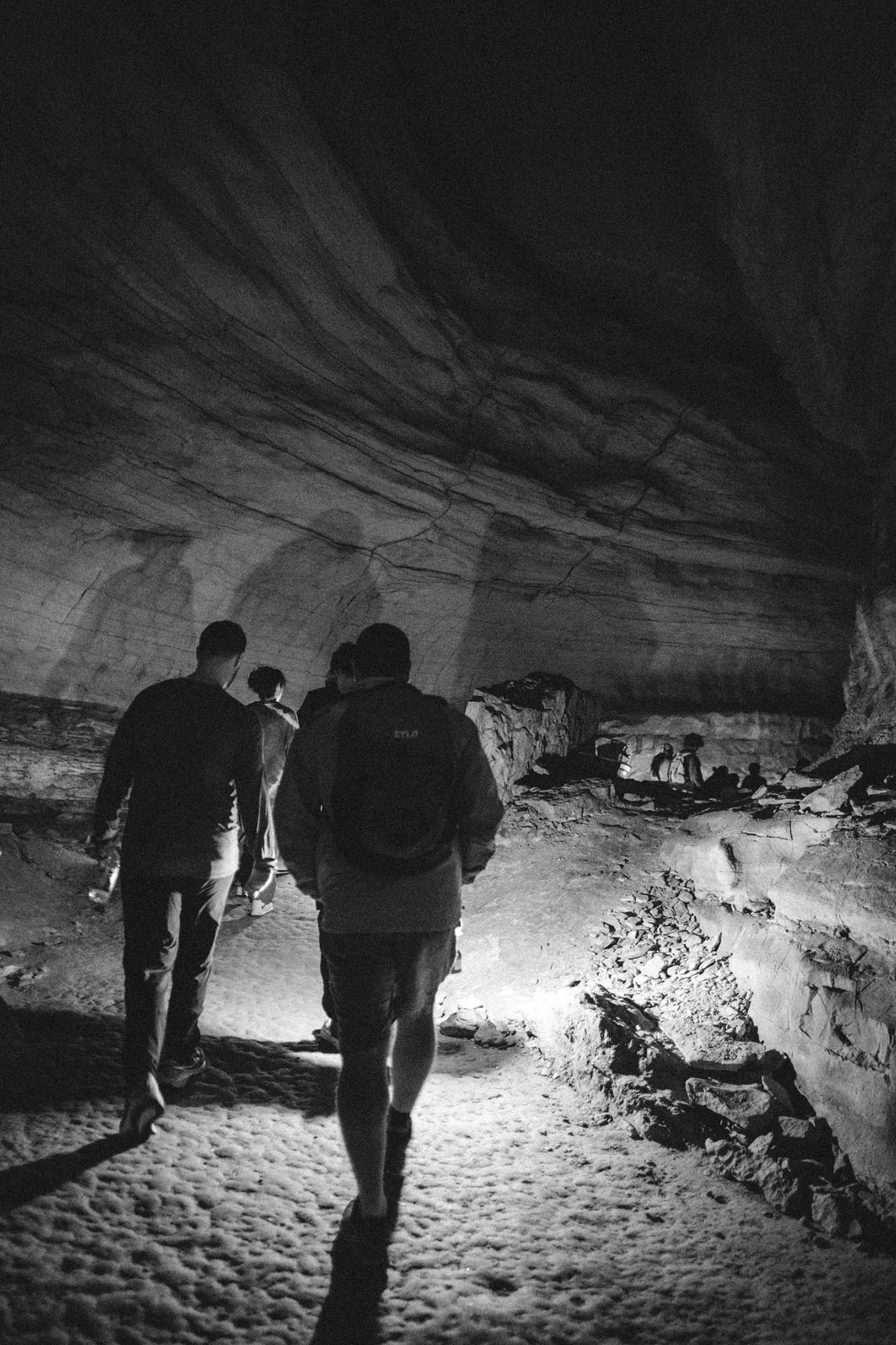 Silhouettes walking in a lantern-lit cave