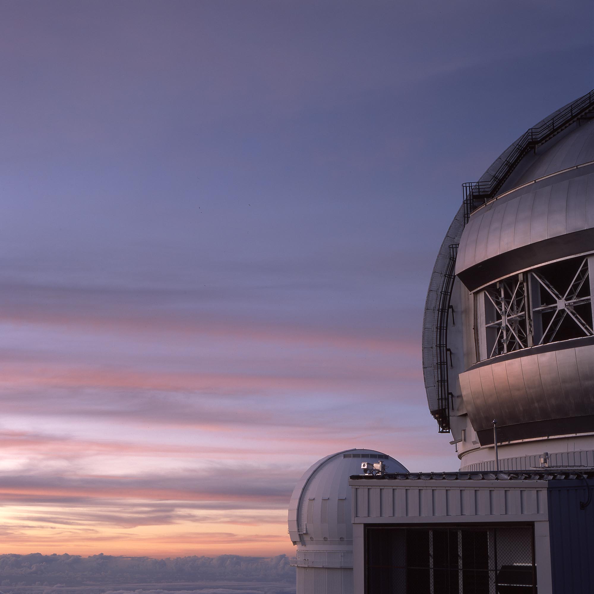 Two observatory buildings above the cloud layer at sunset