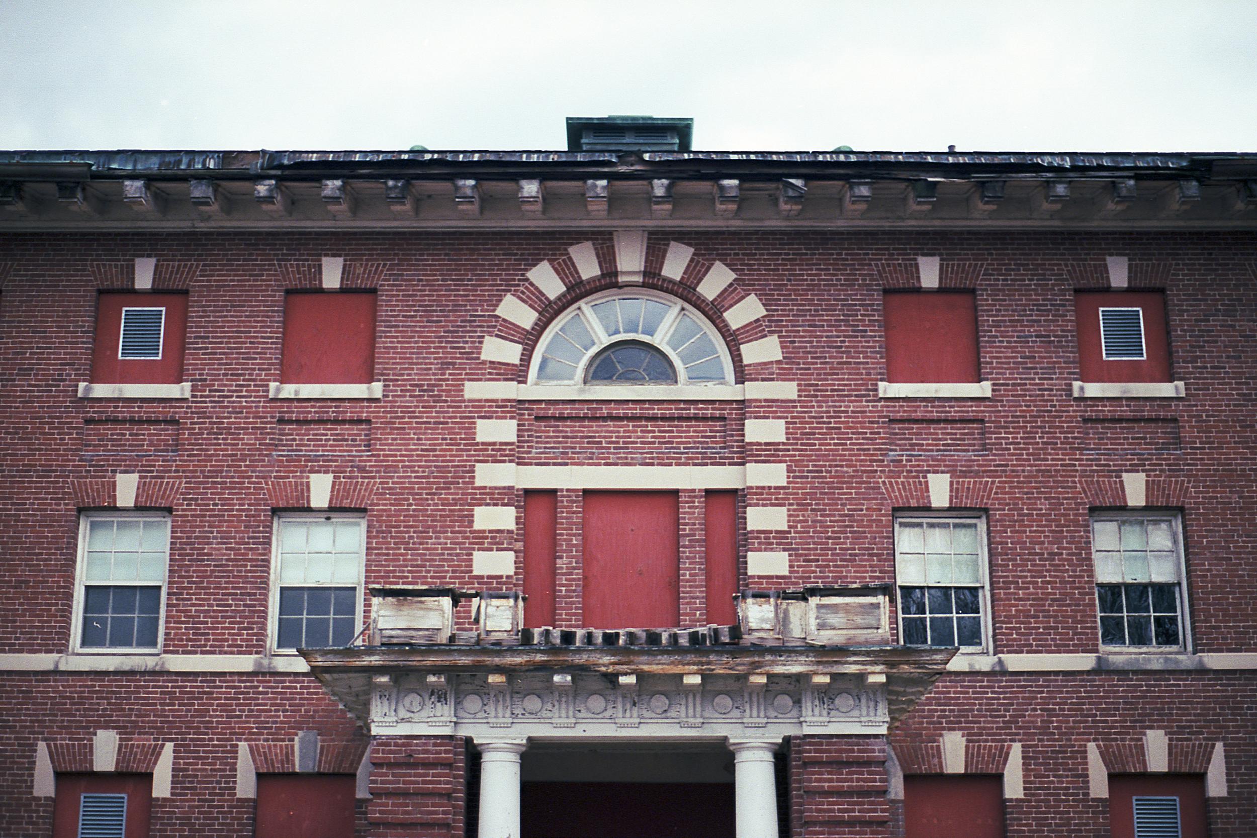 An abandoned hospital building with boarded up windows