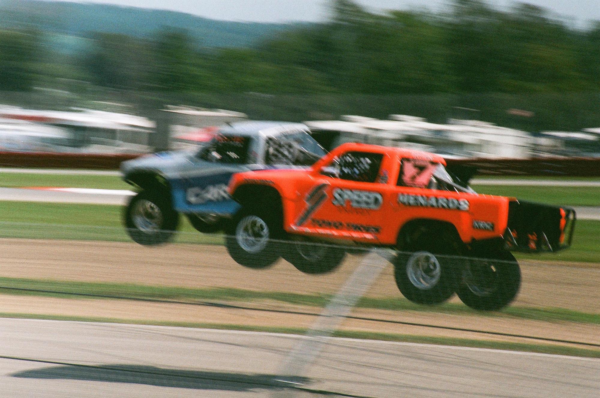 Two Stadium Super Trucks mid-air after going off a jump