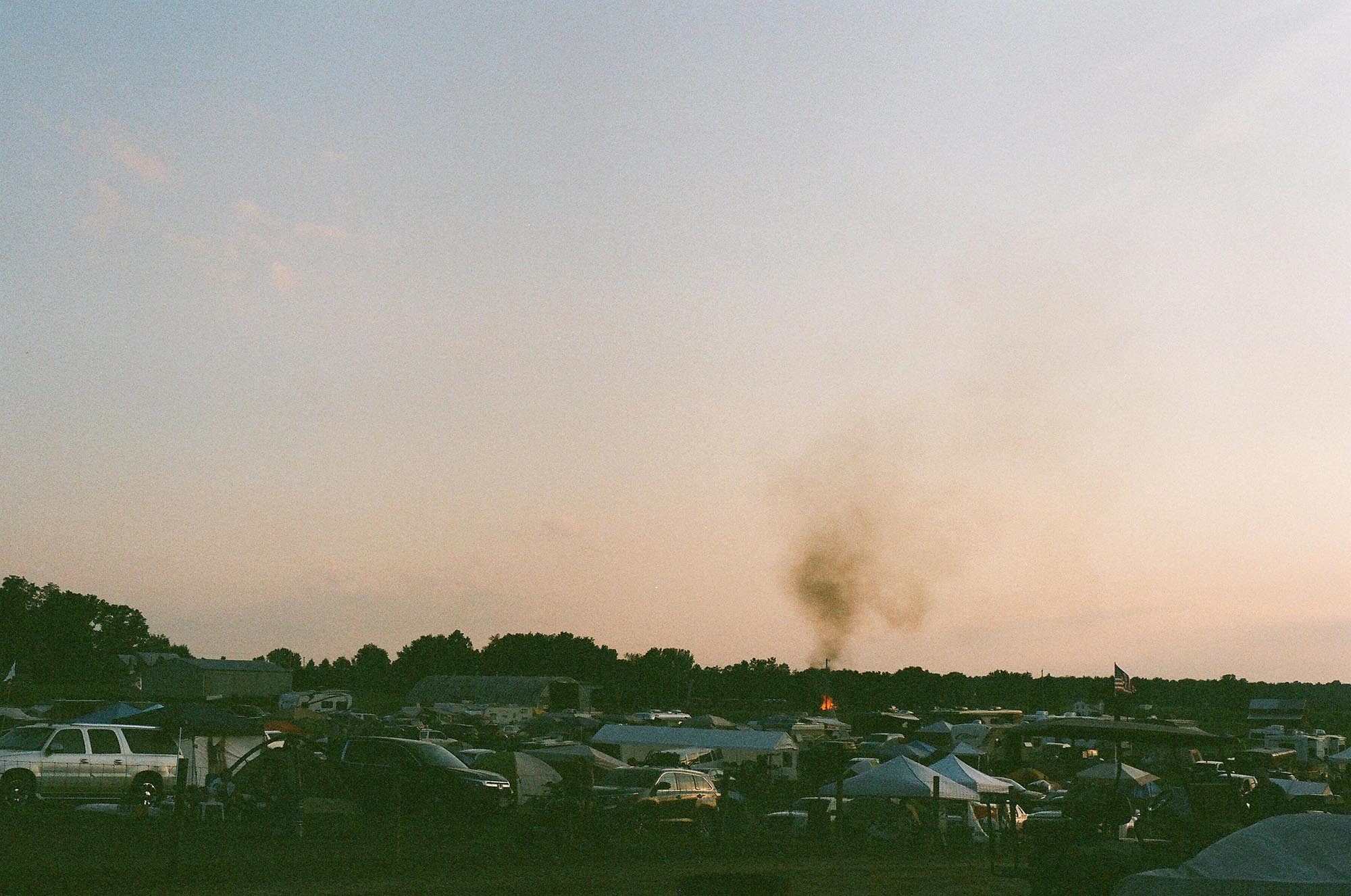 The campground at dusk, smoke from a bonfire in the distance