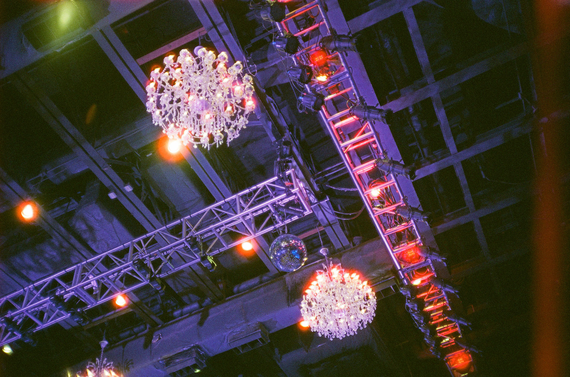 A metal ceiling with exposes trusses and two chandeliers