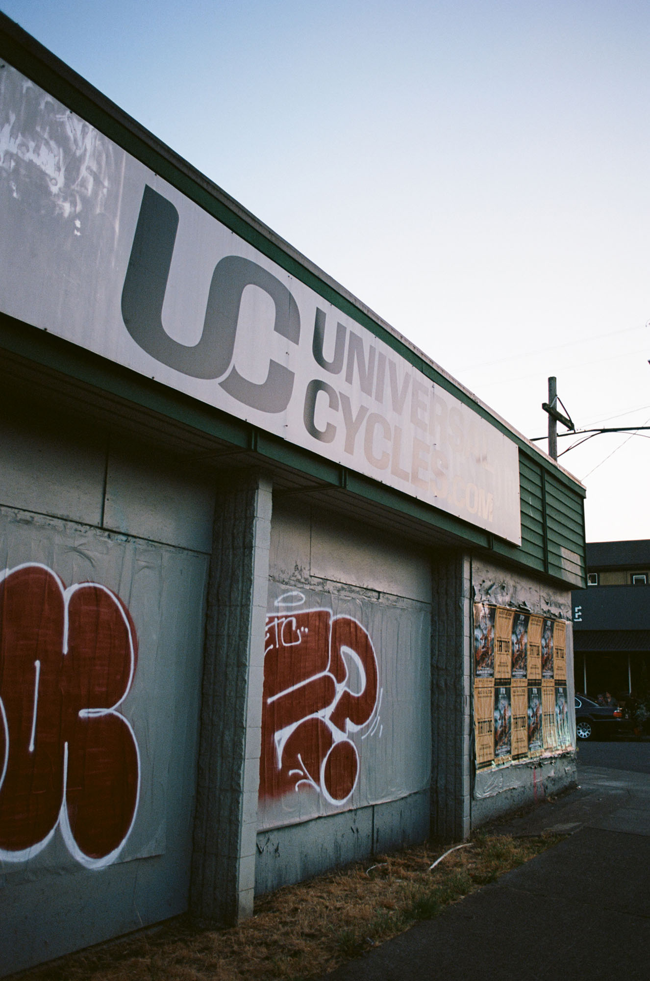 Storefront of a bicycle shop with the doors pulled down, tagged with graffiti