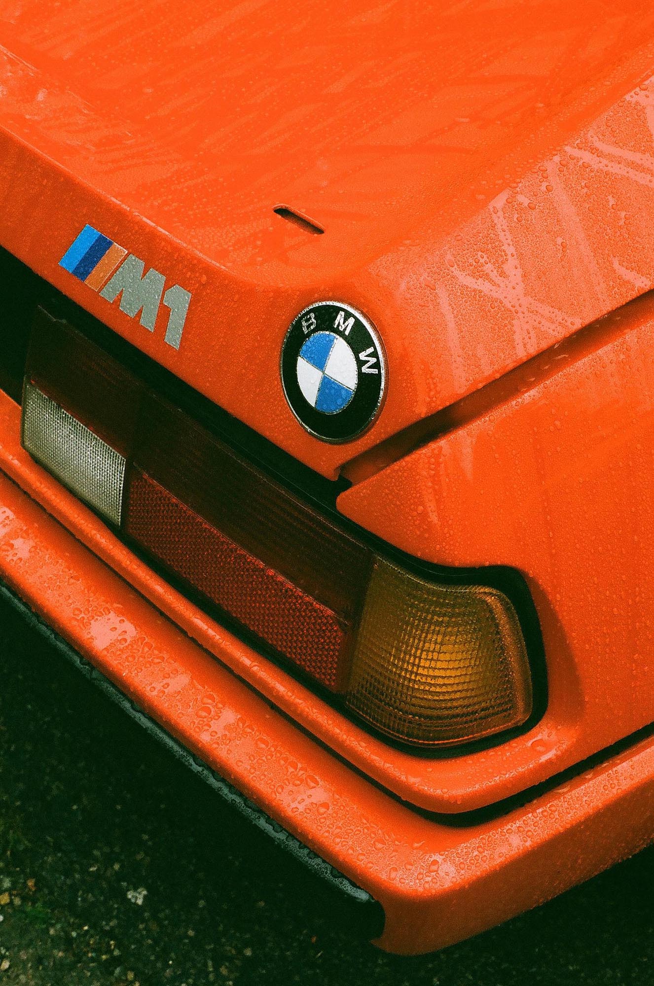 The rear corner of a red BMW M1 in the rain