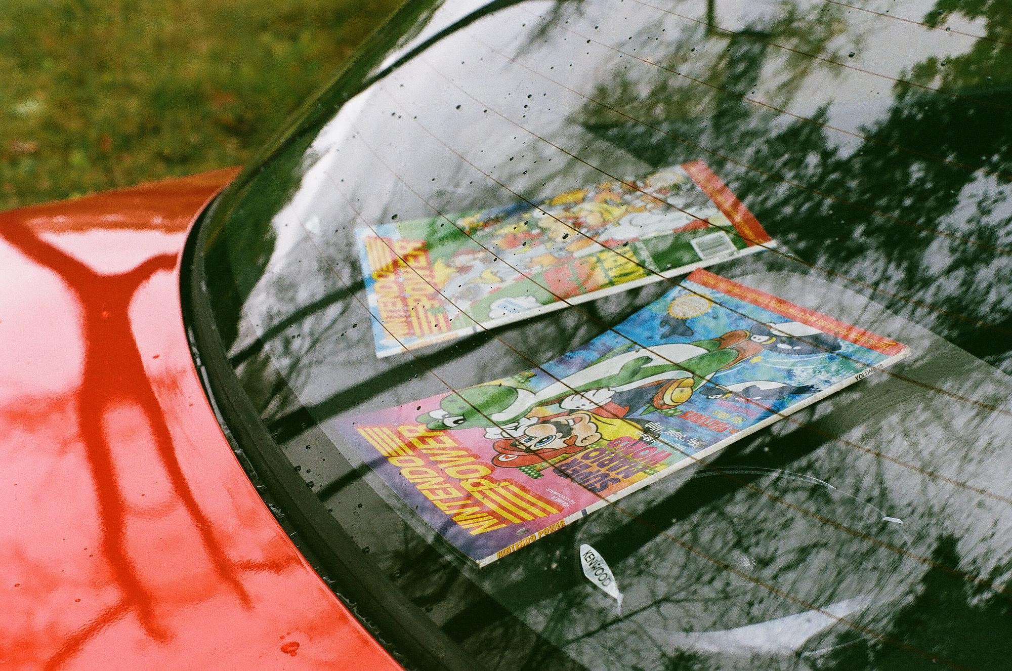 Two issues of Nintendo Power magazine in the rear window of a red Isuzu Stylus