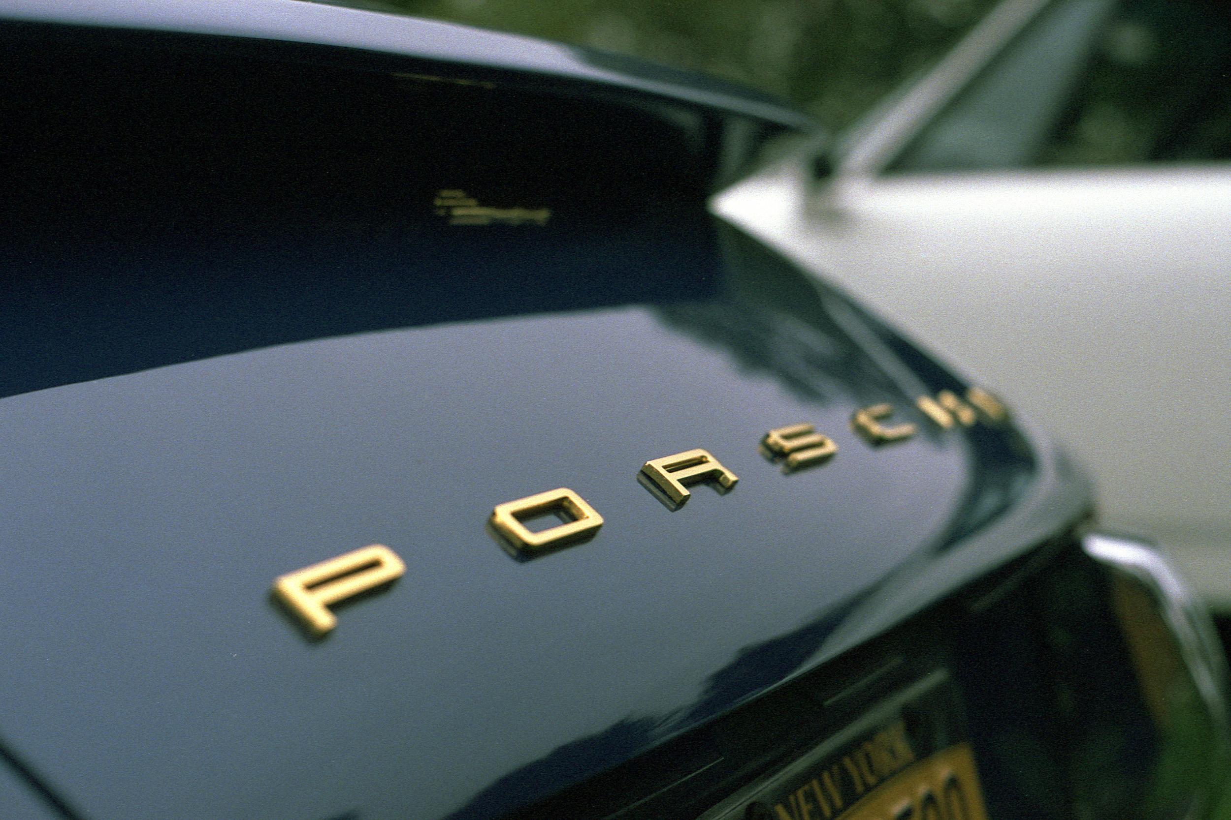 A gold Porsche badge on a dark blue body