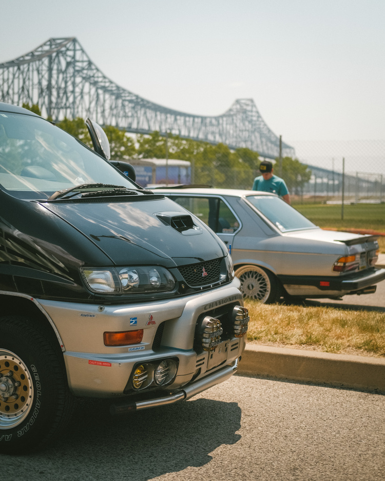 The front end of a Mitsubishi Delica Chamonix in front of a vintage BMW