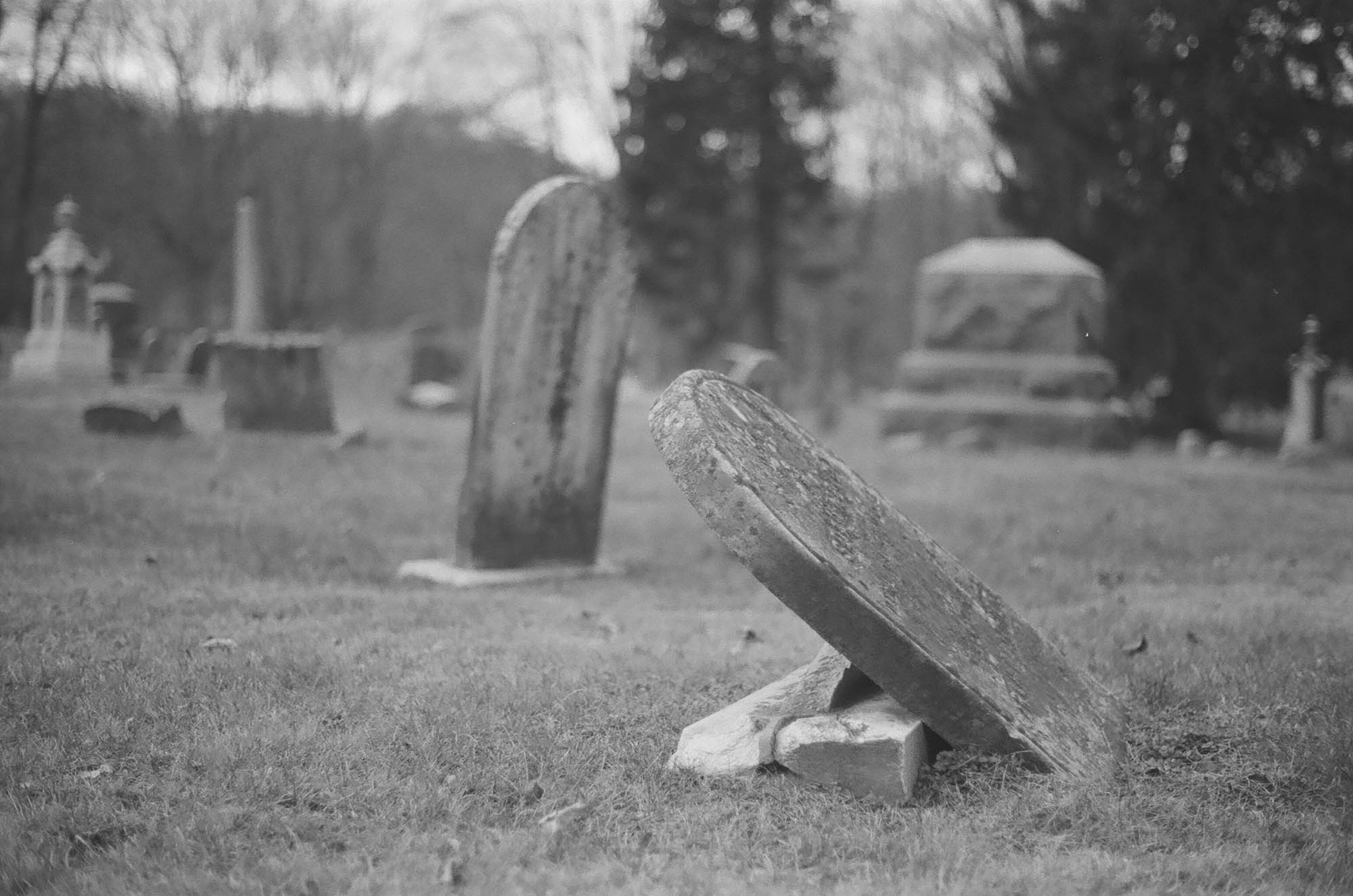 An old headstone tilting over in a cemetery
