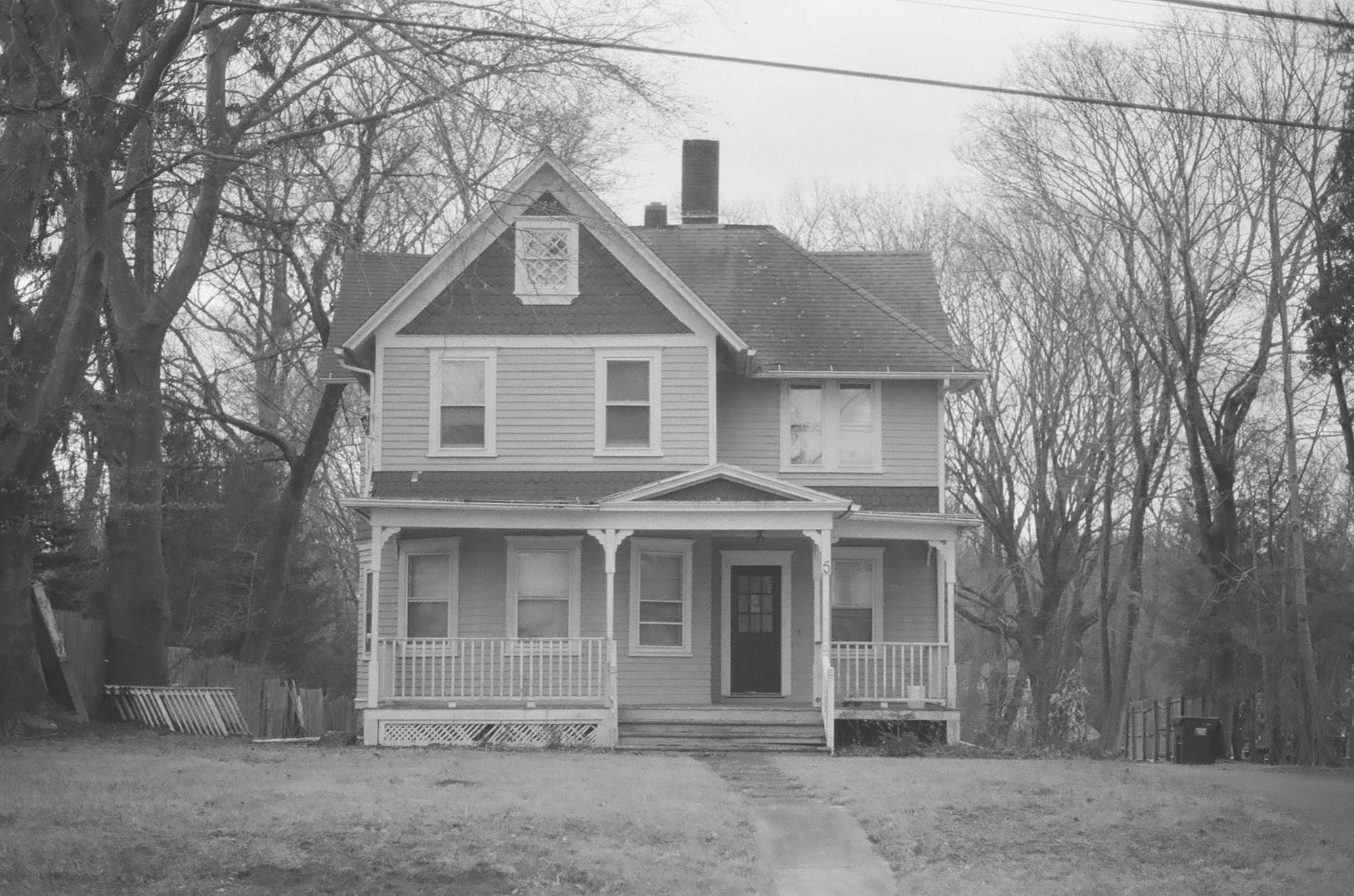 An older two-story house with different tones of siding