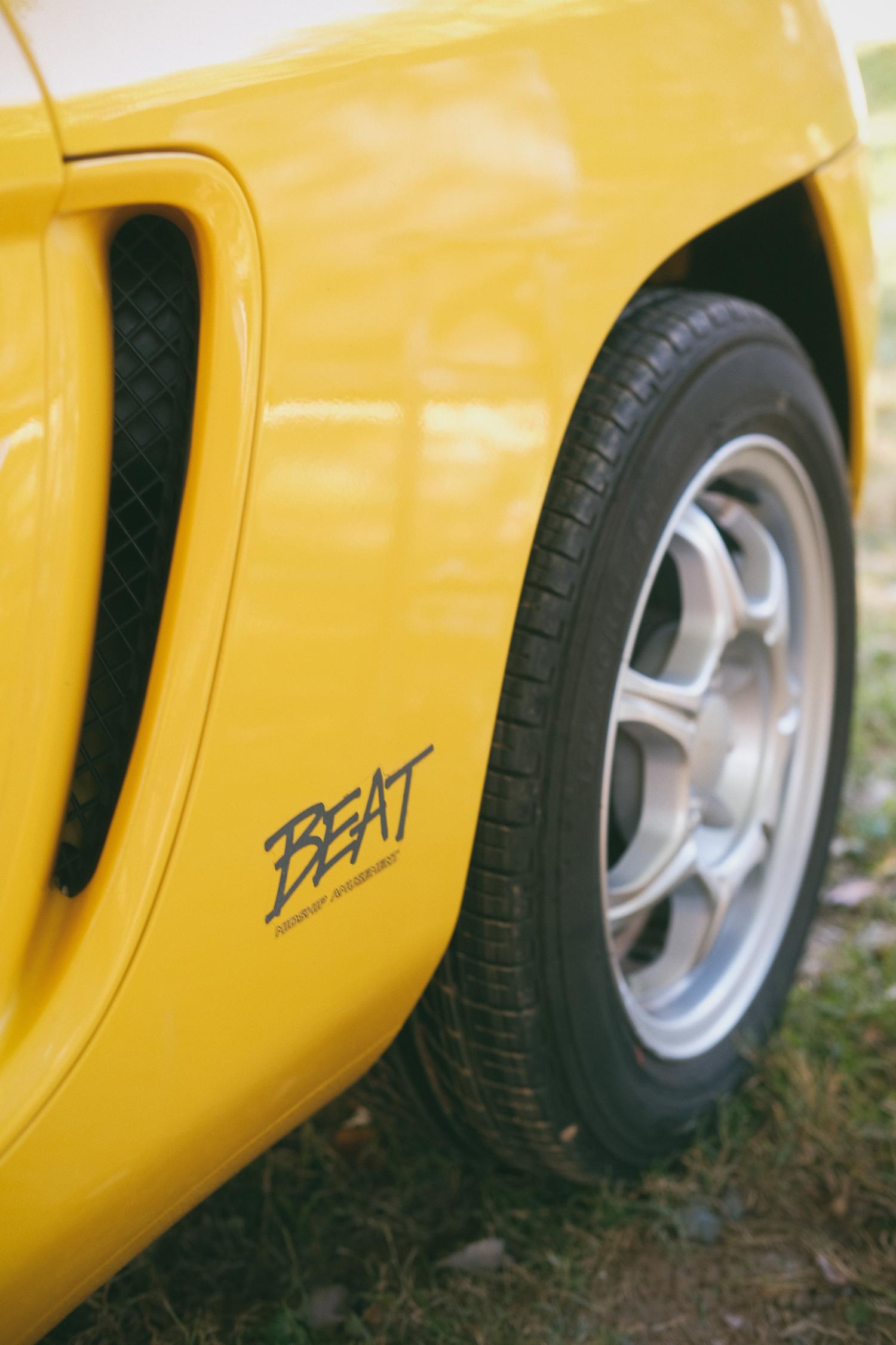 The rear wheel and vent of a yellow Honda Beat