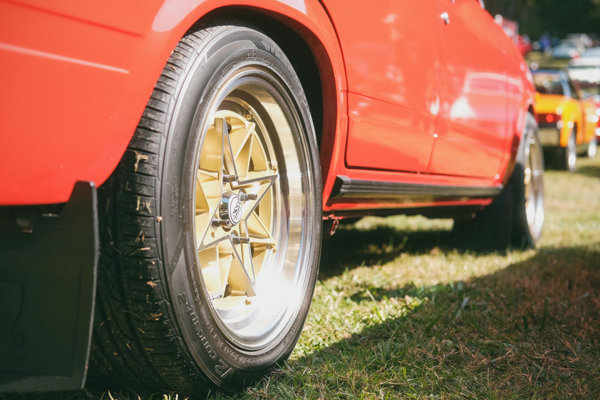 A gold rear wheel of a red Lada