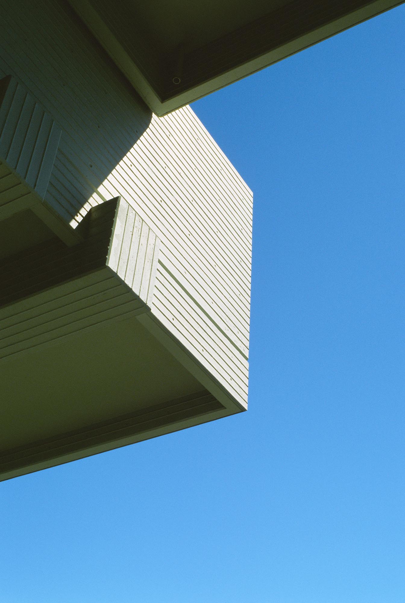 An abstract exterior corner overhang against a blue sky