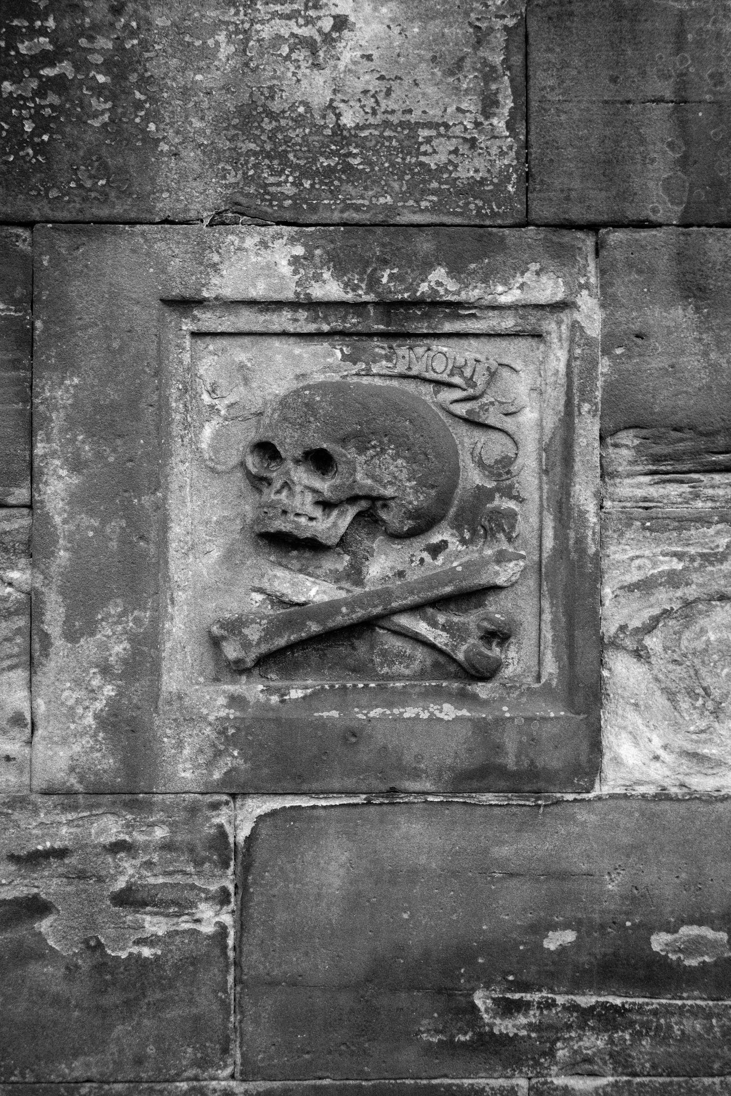 A Memento Mori skull relief carved into a stone wall