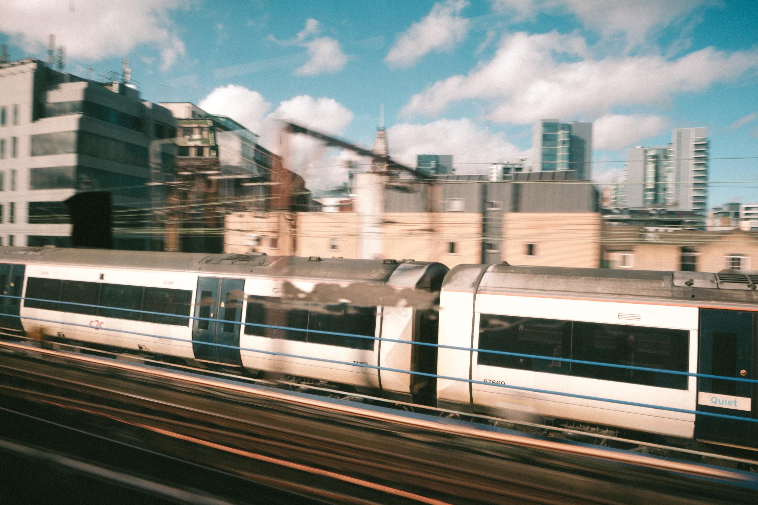 A London subway train in front of a blurry city background