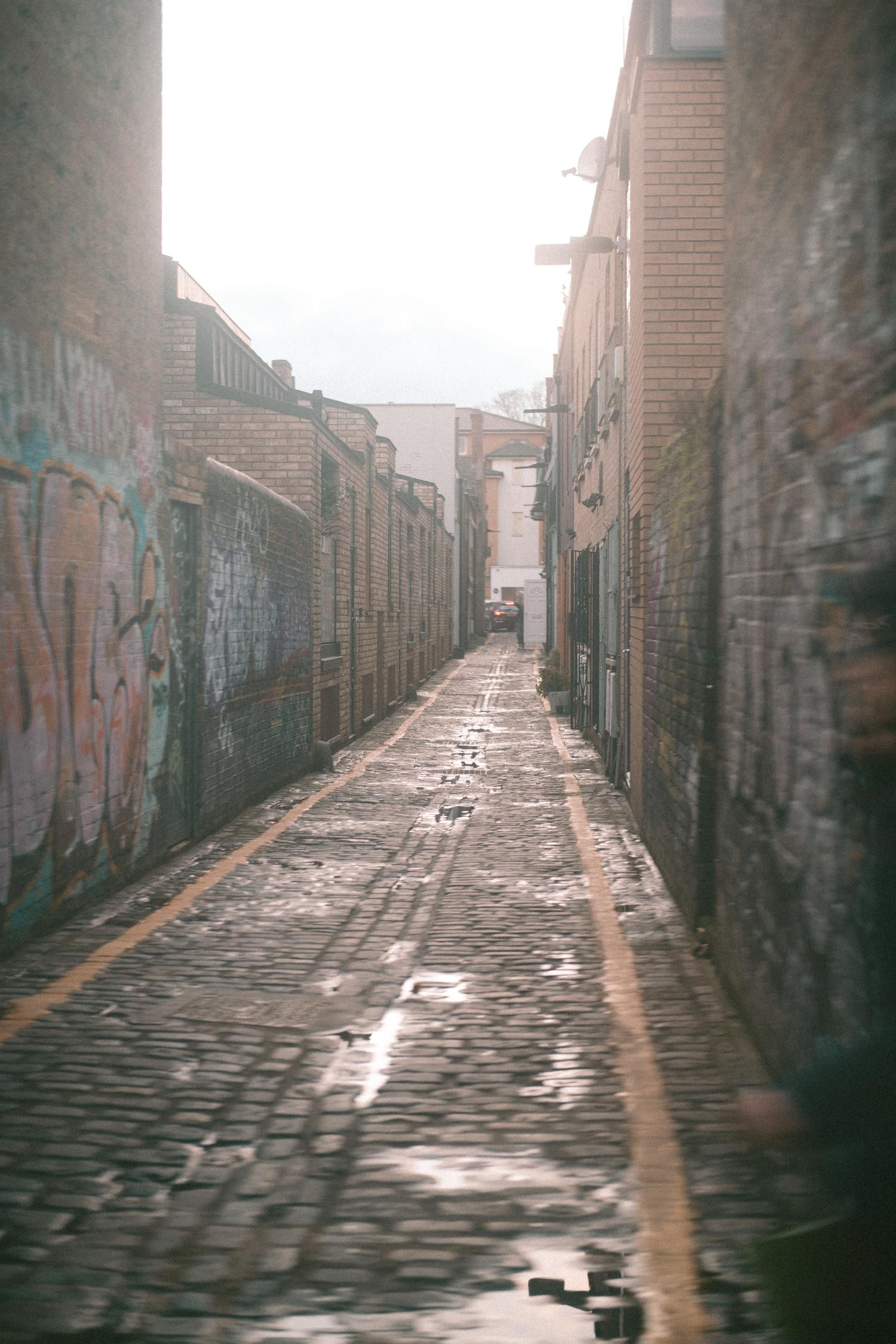 A brick alleyway with puddles