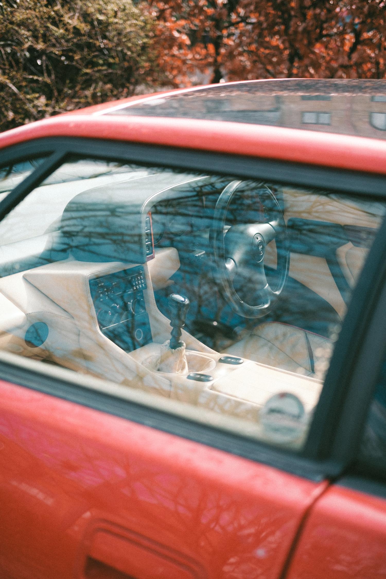 Looking through the driver's side window at the interior of a red Lotus Esprit