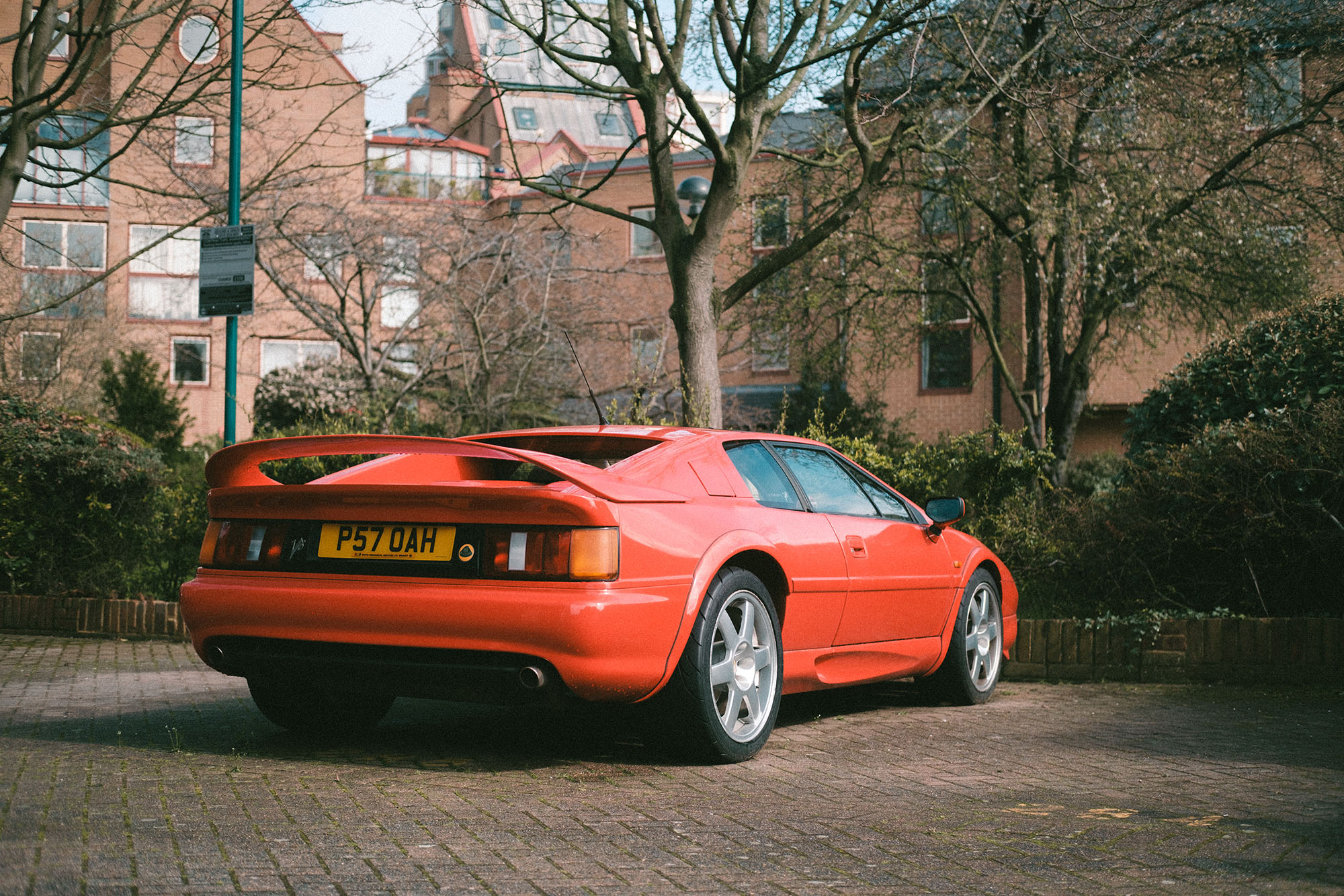 A red Lotus Esprit parked at a London brick housing complex