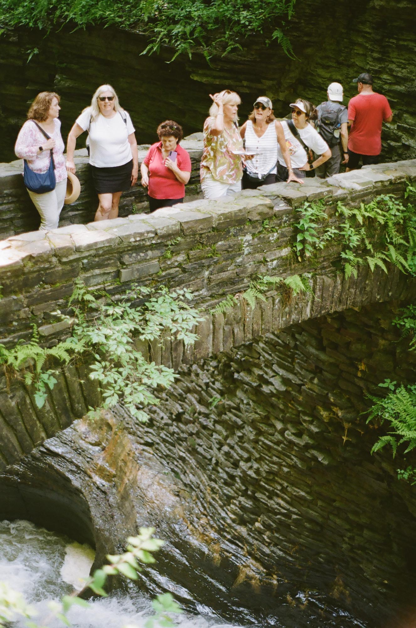 A group of people crowded on a small stone bridge above the gorge