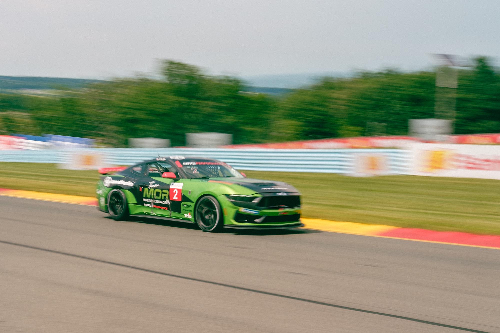 A blurry Ford Mustang Dark Horse on track