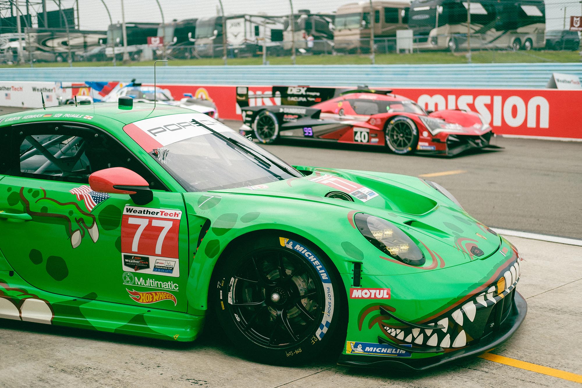 Rexy the Porsche in front of a Porsche 963 in pit lane