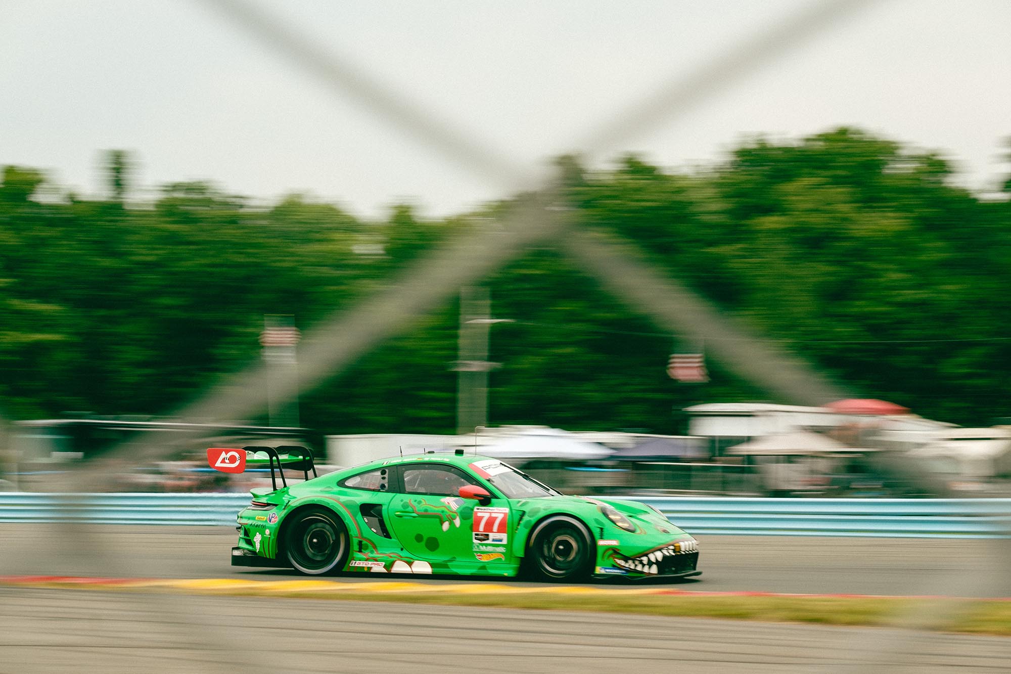 Rexy the Porsche on track through a chain link fence