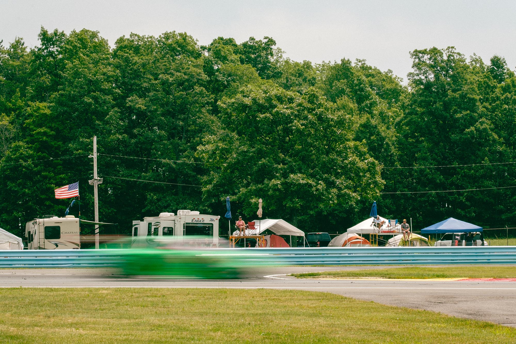 A blurred car on track in front of trackside spectators