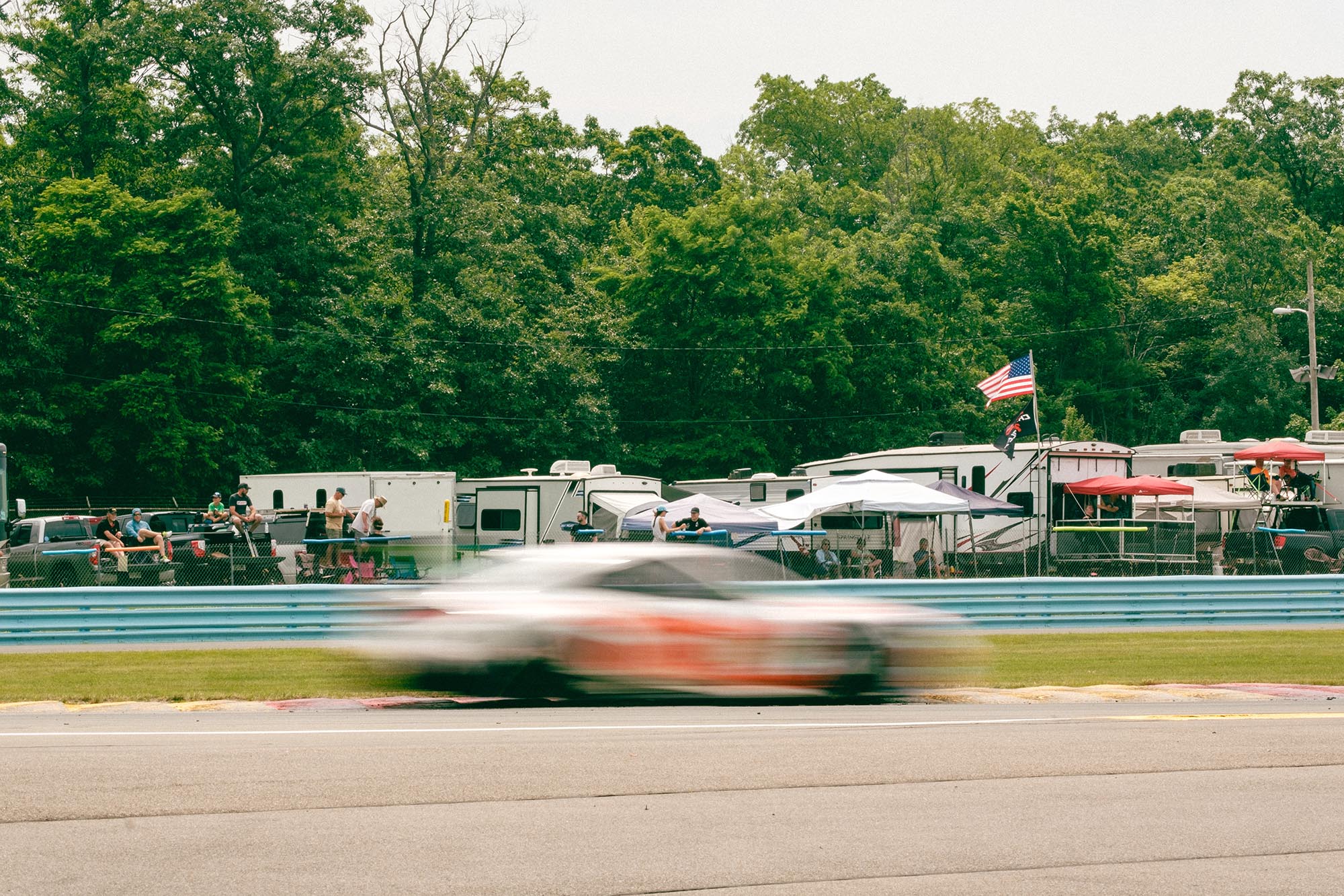 A blurred car on track in front of trackside spectators