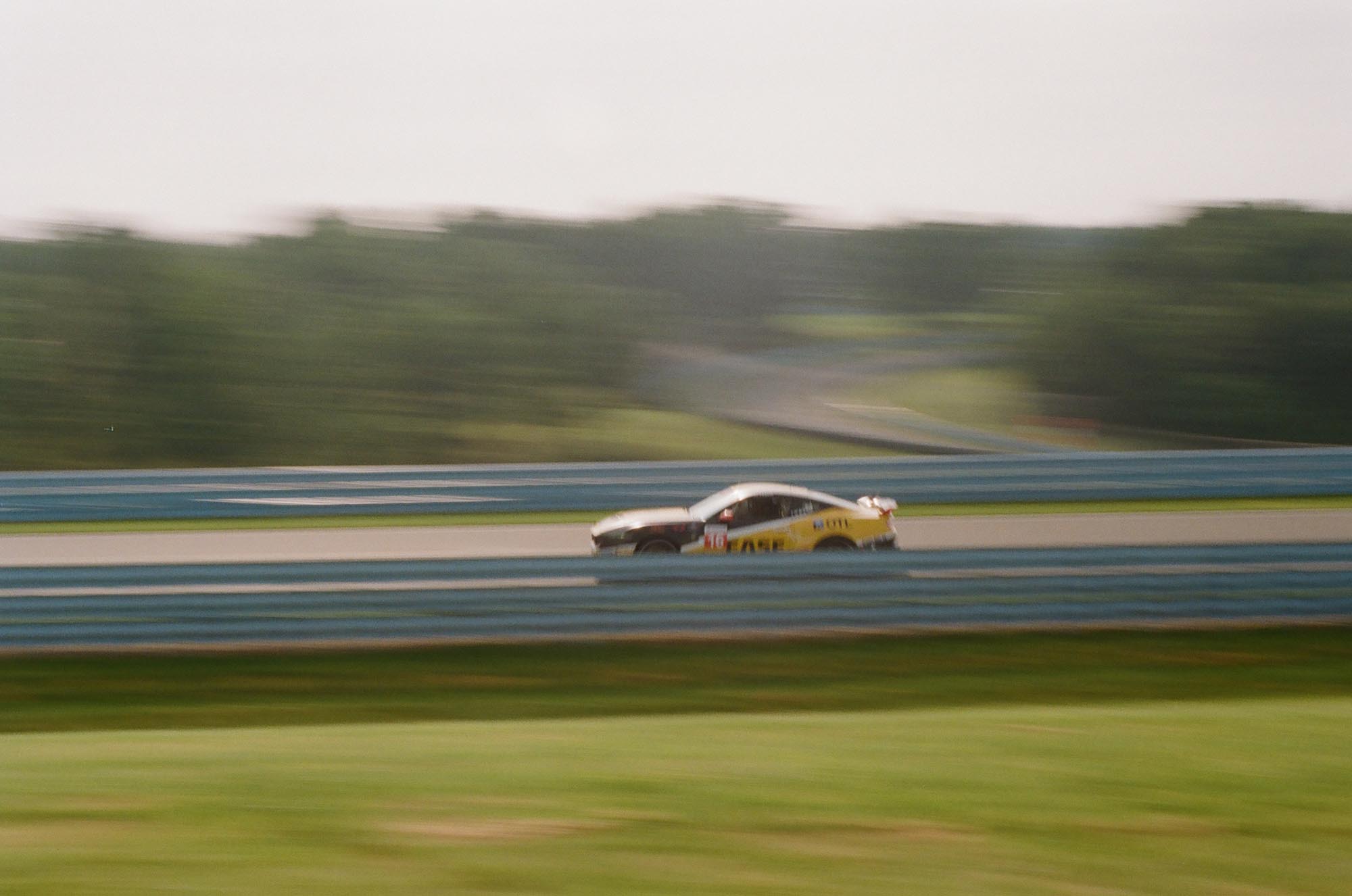 A Ford Mustang Dark Horse driving on a blurry track