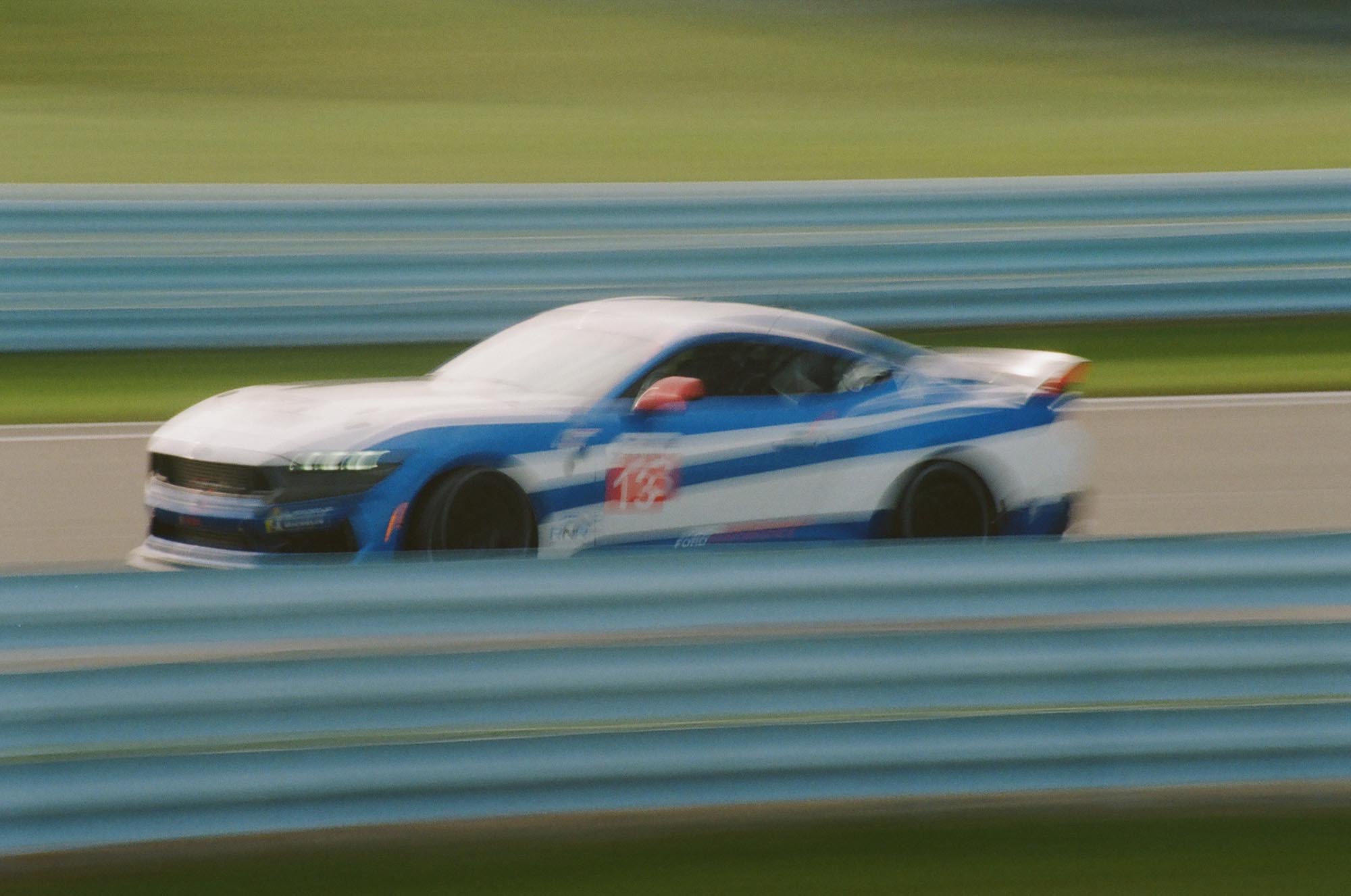 A Ford Mustang Dark Horse driving on a blurry track